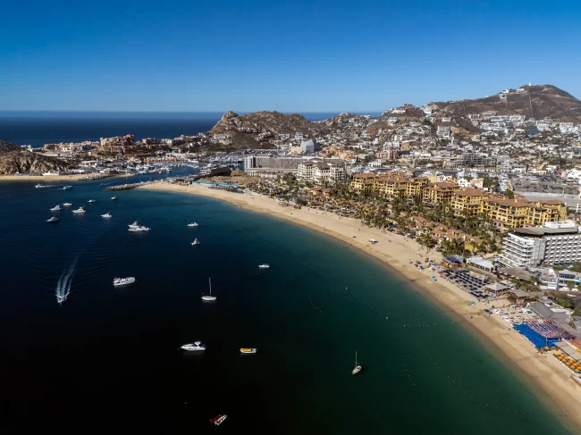 Aerial view of Cabo San Lucas marina and Medano Beach with boats, coastline, and cityscape in the morning