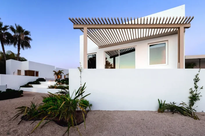 Modern white luxury villa exterior in Los Cabos with minimalist Baja architecture, pergola roof detail, and desert landscaping.